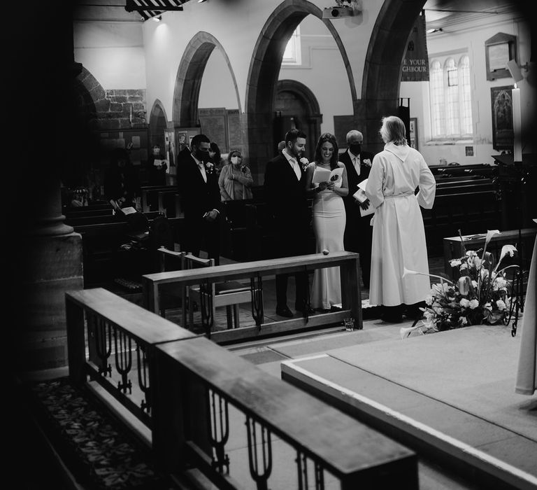 Bride and groom reading hymns at the altar at their church micro wedding