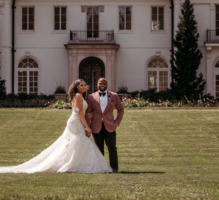 Bride & groom stand within green gardens on their wedding day