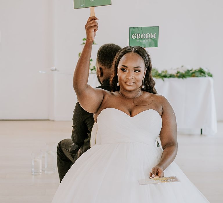 Bride & groom lift 'Groom' sign for Mr & Mrs game during wedding reception