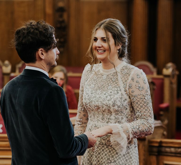 Bride looks lovingly at her groom as she wears Needle And Thread wedding gown with her brown hair tied back