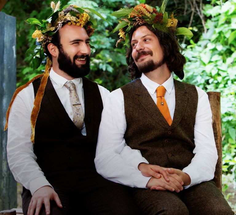 Grooms laugh and smile whilst looking at one another on their wedding day