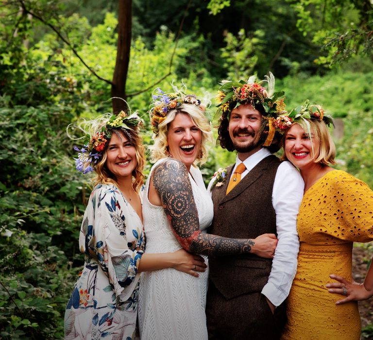 Groom stands with his groomsmaids who wear brightly coloured gowns in different colours and styles