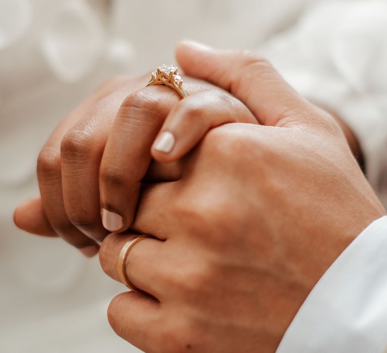 Bride and groom hold hands showing off their rings at Wasing Park wedding