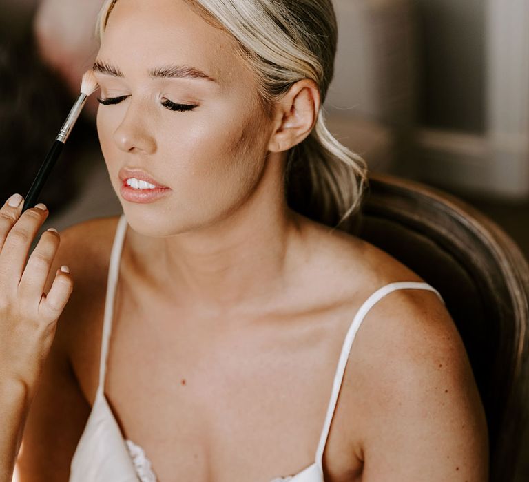 Bride on the wedding morning in satin pyjamas having her natural wedding day makeup done