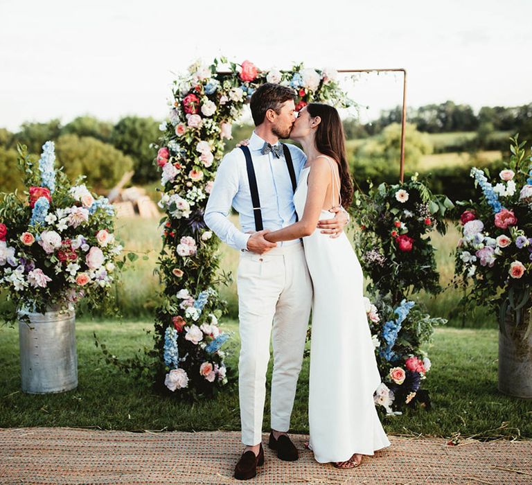 Bride & groom wrap their arms round one another on their wedding day outdoors