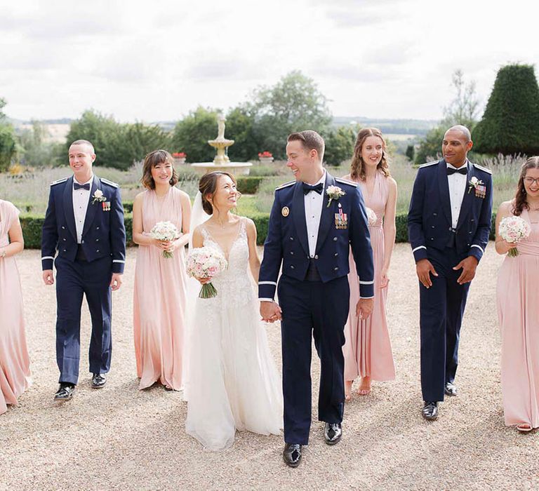 Bride & groom walk together as bridesmaids and groomsmen follow