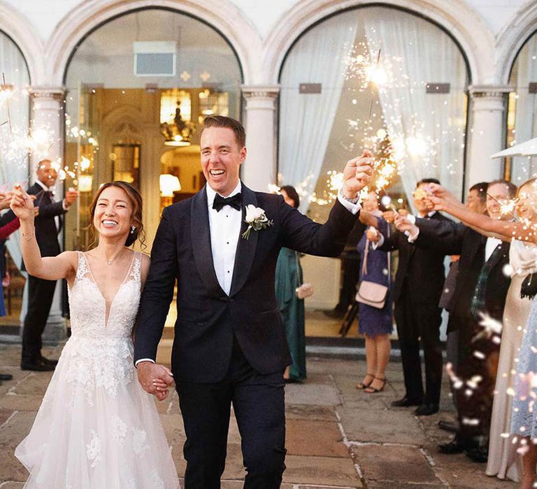 Bride & groom and wedding guests hold sparklers outdoors