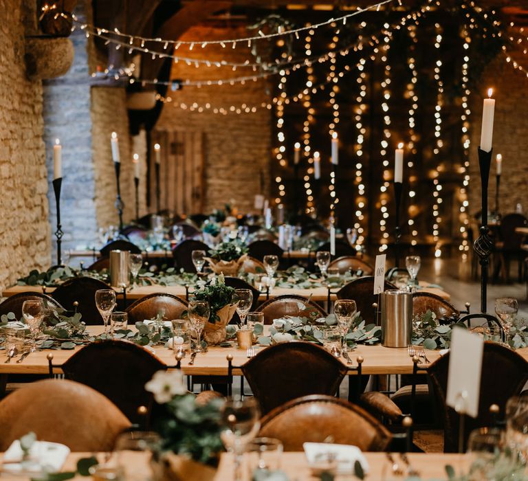 Rustic barn wedding reception with candles, fairy light, wooden tables and table garlands