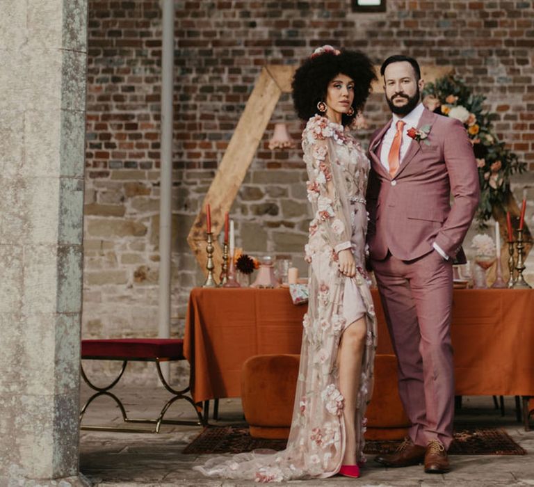 Black bride in a pink embroidered wedding dress with her groom in a pink wedding suit at Chiddingstone Castle 