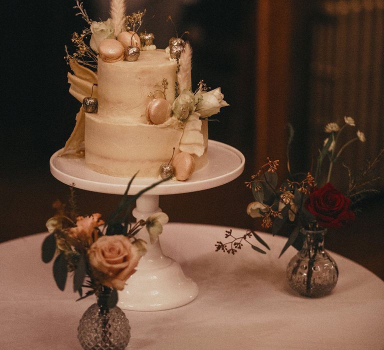 2 tier wedding cake complete with light frosting, macaroons and silver dipped cherries 