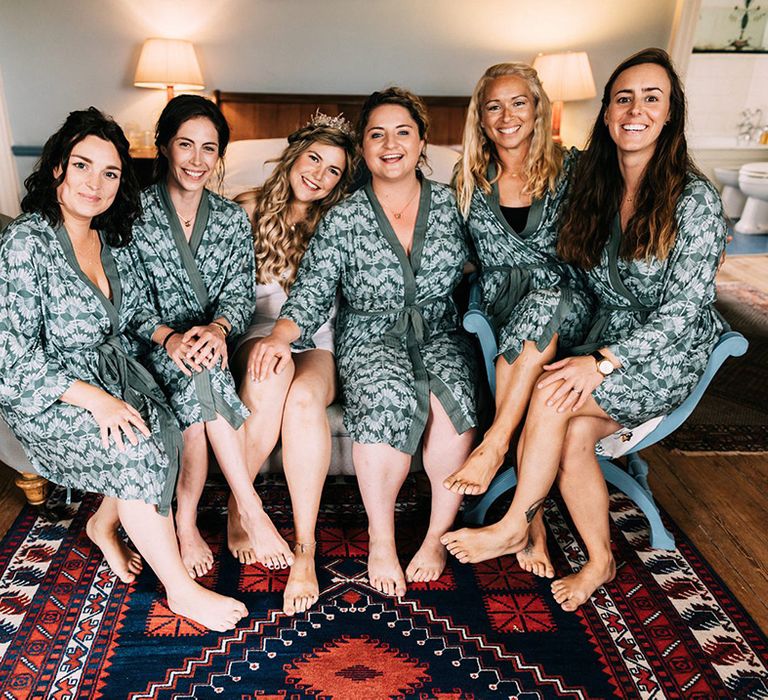 Bride smiling with the bridesmaids in their matching robes as they get ready for the day 