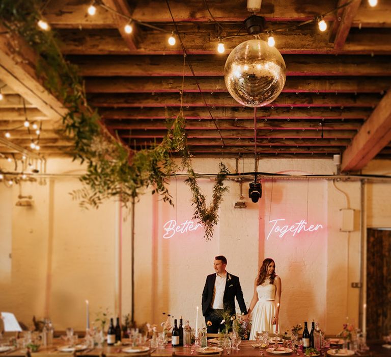 Bride and groom at 100 Barrington wedding venue with neon pink 'Better Together' sign and disco ball 