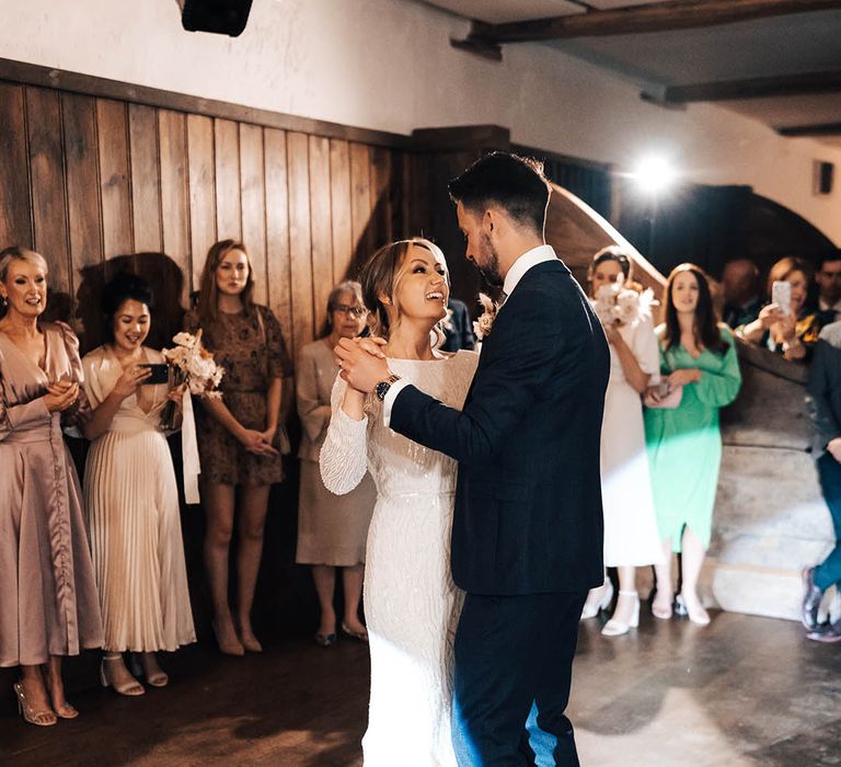 Bride and groom share their first dance togther as their wedding guests watch on