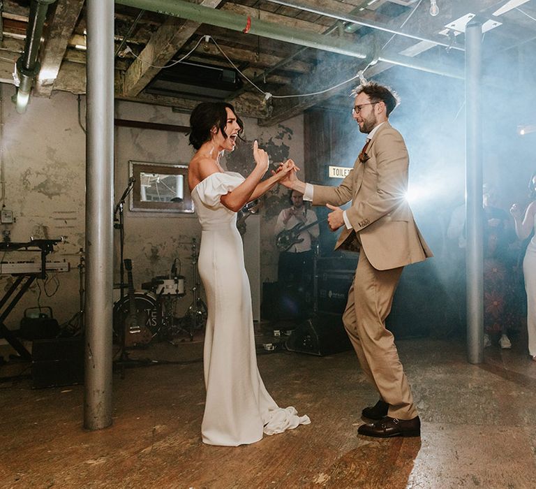 Bride and groom get the party started on the dance floor for 70s party wedding in industrial venue