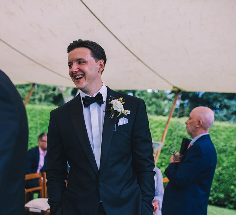 Smiling groom in black tie with white flower buttonhole and handkerchief