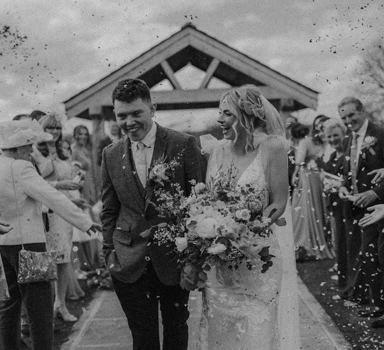 Bride with braided hairstyle smiles as she has confetti exit with the groom 