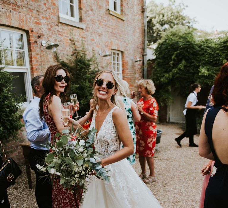 Bride in a princess wedding dress with tulle skirt wearing sunglasses at summer wedding 