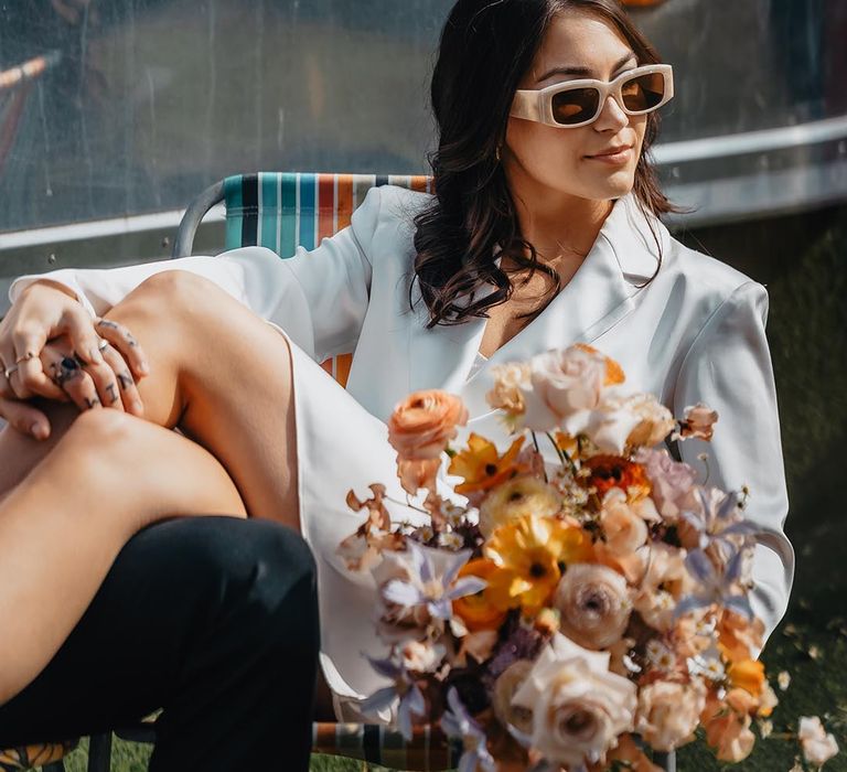 Retro bride in beige sunglasses and a short wedding dress at a rooftop wedding 