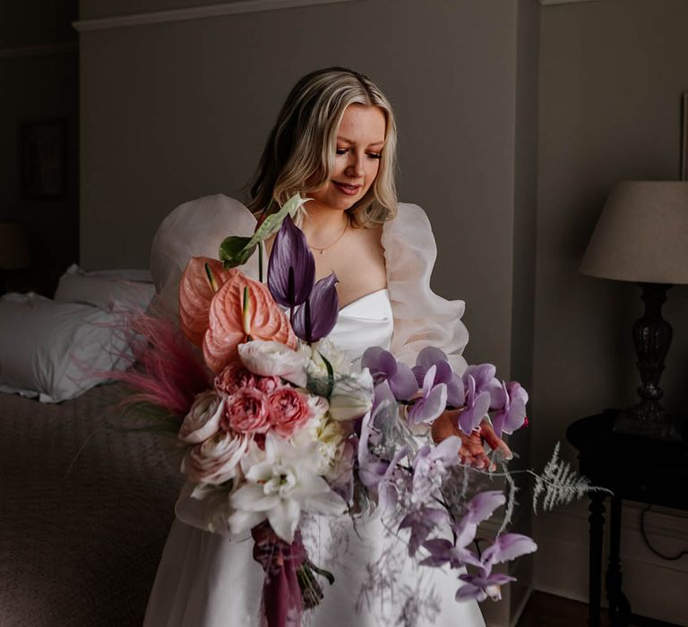 Bride in a JESUS PEIRO wedding dress holding a lilac orchid, pink anthurium and white lily bouquet 