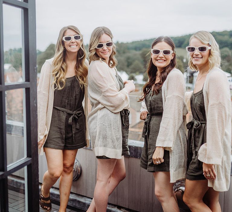 Bridesmaids in sunglasses and matching khaki playsuits and cardigans 