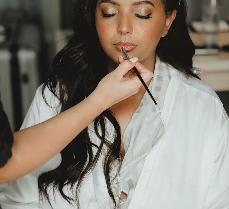 Black bride wears natural makeup and glossy lips with her black hair in loose waves on her wedding day 