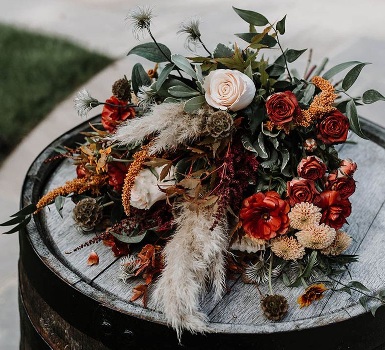 Autumnal wedding bouquet with orange flowers and dried grass