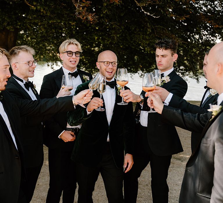 Groom wears black tie surrounded by his groomsmen in matching suits 