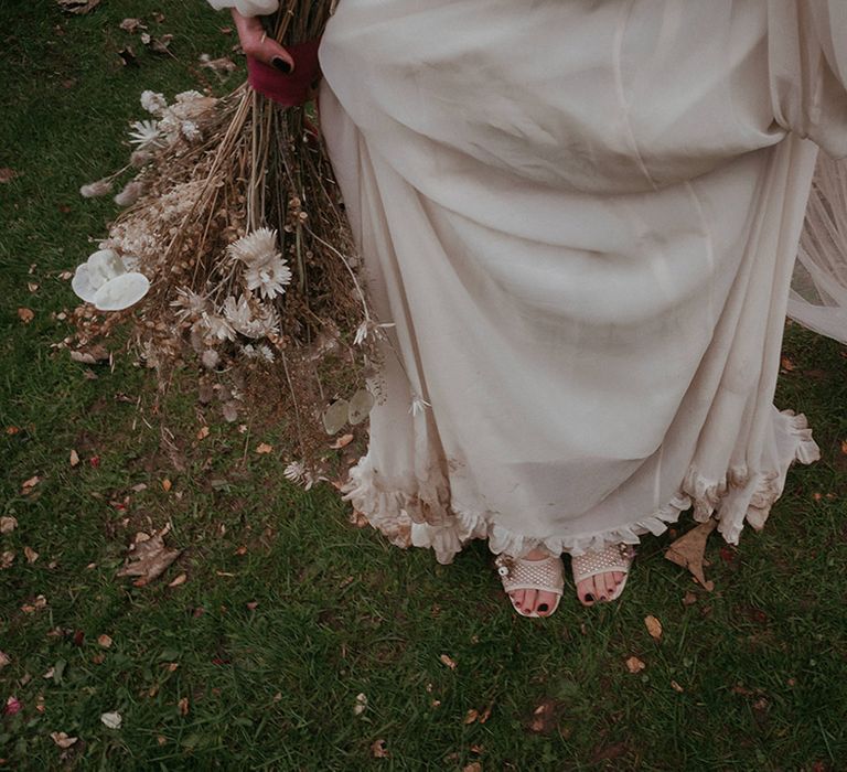 Bride holds dried floral bouquet and wears peep toe heeled shoes 