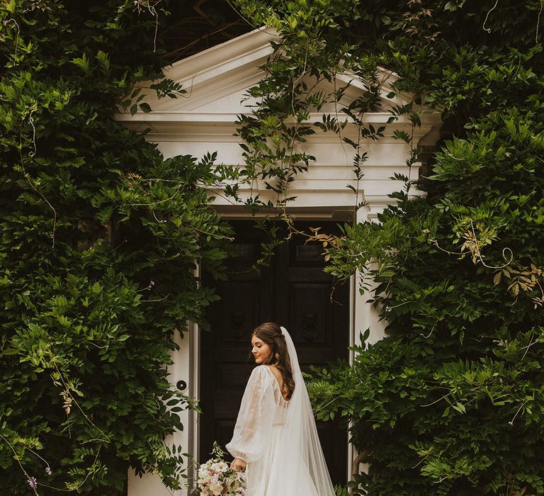 Bride in a puff balloon sleeve wedding dress standing at Sprivers Mansion country house wedding venue 