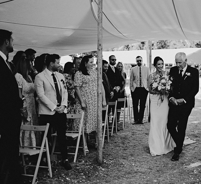 Father of the bride walks the bride down the aisle for outdoor ceremony 