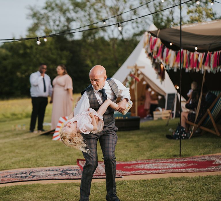 Wedding guest plays with child outdoors in front of Moroccan styled carpets 