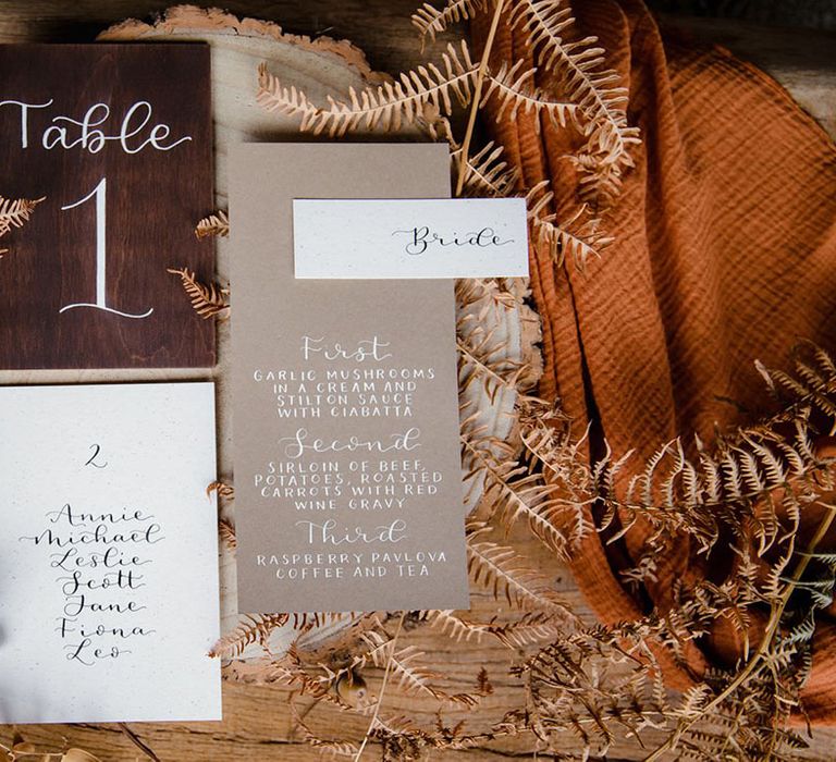 Boho inspired wedding stationery with neat calligraphy on wooden stump with dried flower decorations