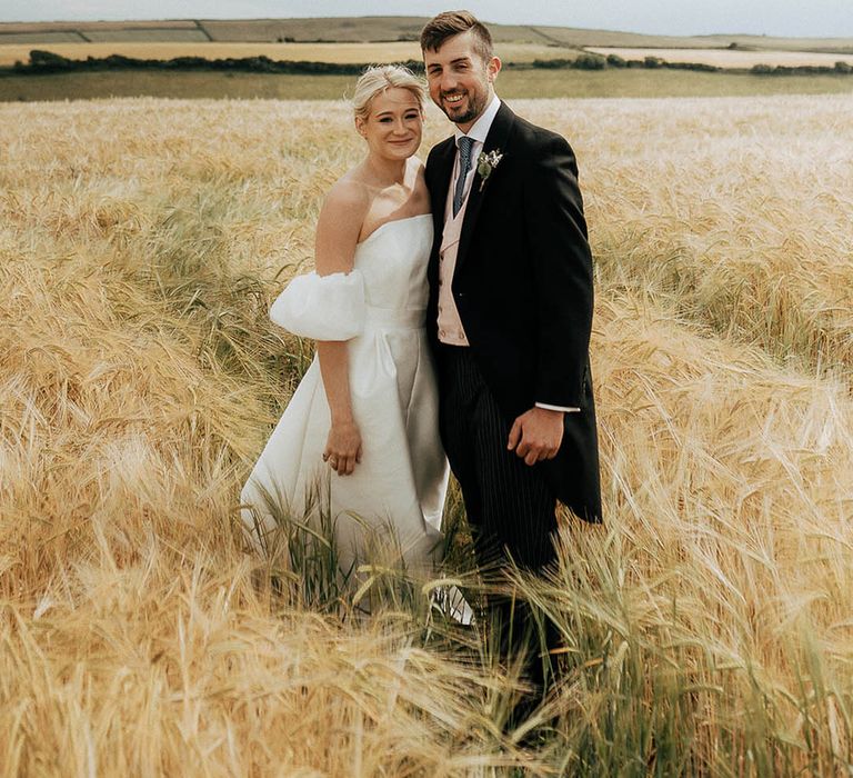 Bride and groom walk through golden fields during couples portraits outdoors 