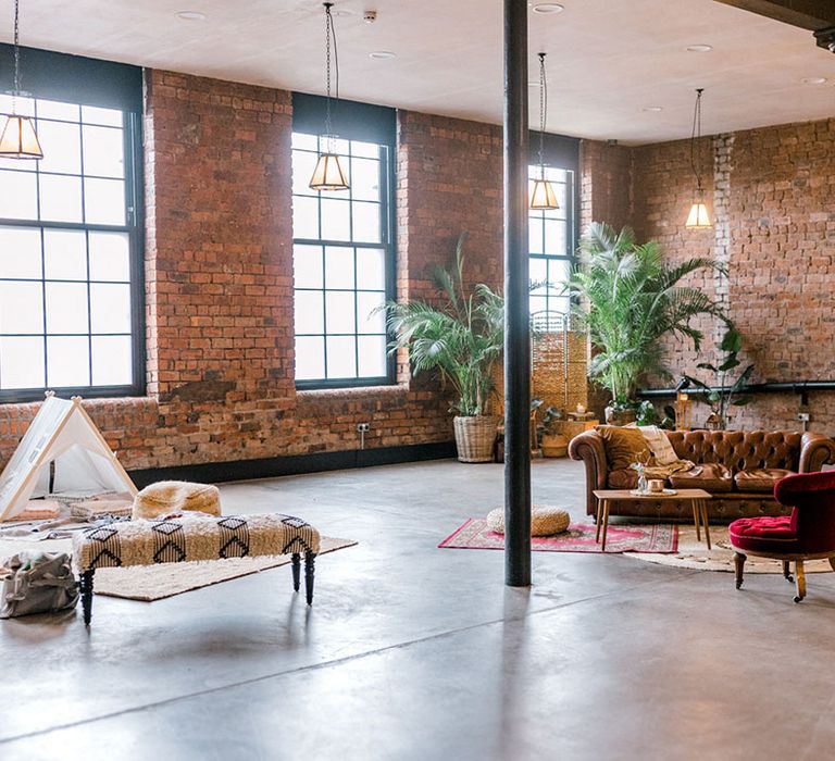 Relaxed seating area with brown leather sofa and children's tent beside Moroccan styled rugs 