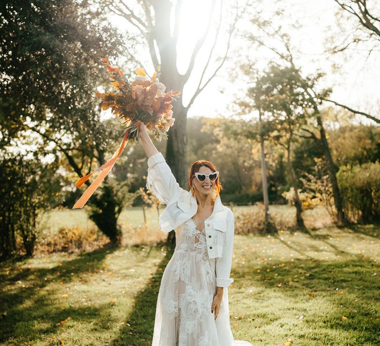 Bride wears heart shaped sunglasses and white denim bridal jacket with glittering tassels and customised back 