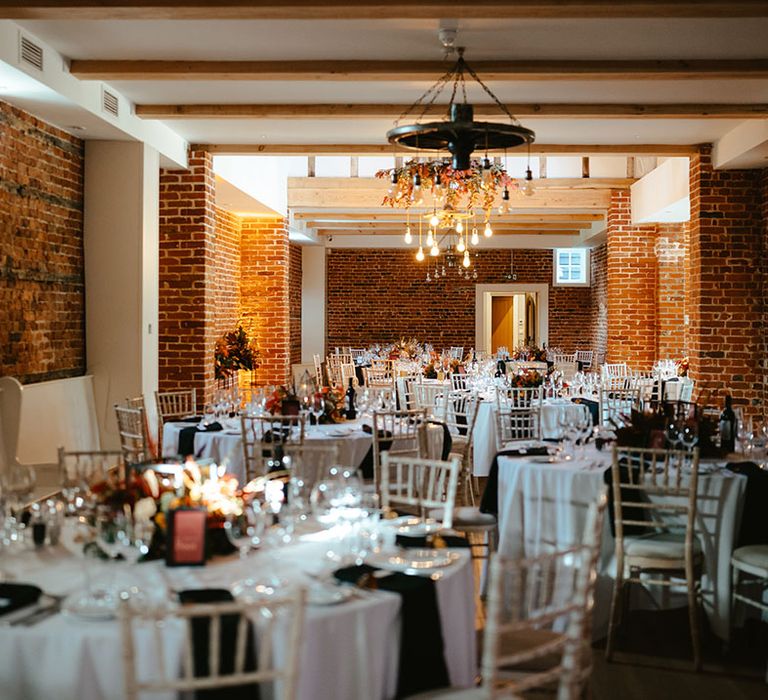 Reymerston Hall wedding venue complete with round tables, festoon light chandelier and burnt orange wedding flowers with Autumnal feel 