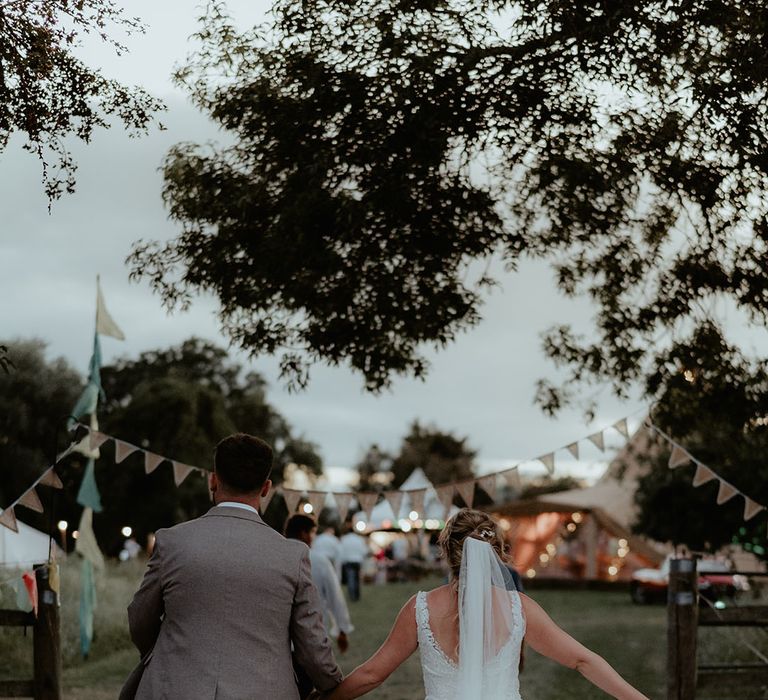 Bride & groom walk toward Buffalo Tipi during festival wedding reception 