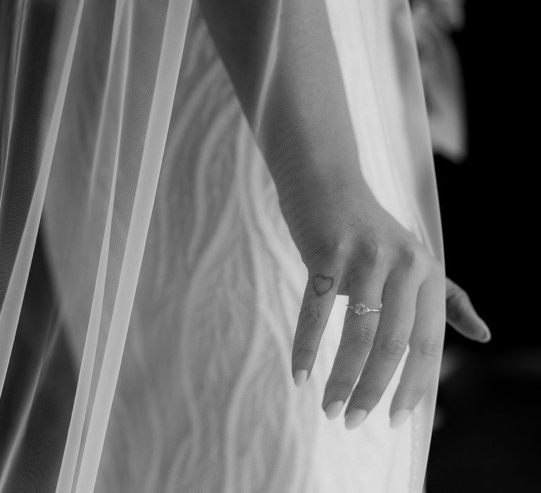 Bride with neutral colour wedding nails with simple diamond wedding ring wearing a cathedral length veil 