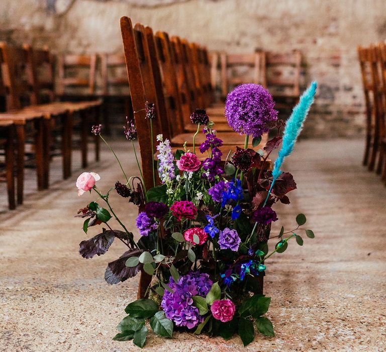 Purple hydrangeas, pink garden roses, purple orchids, lilac carnations, dried flowers and peacock blue feathers aisle flowers 