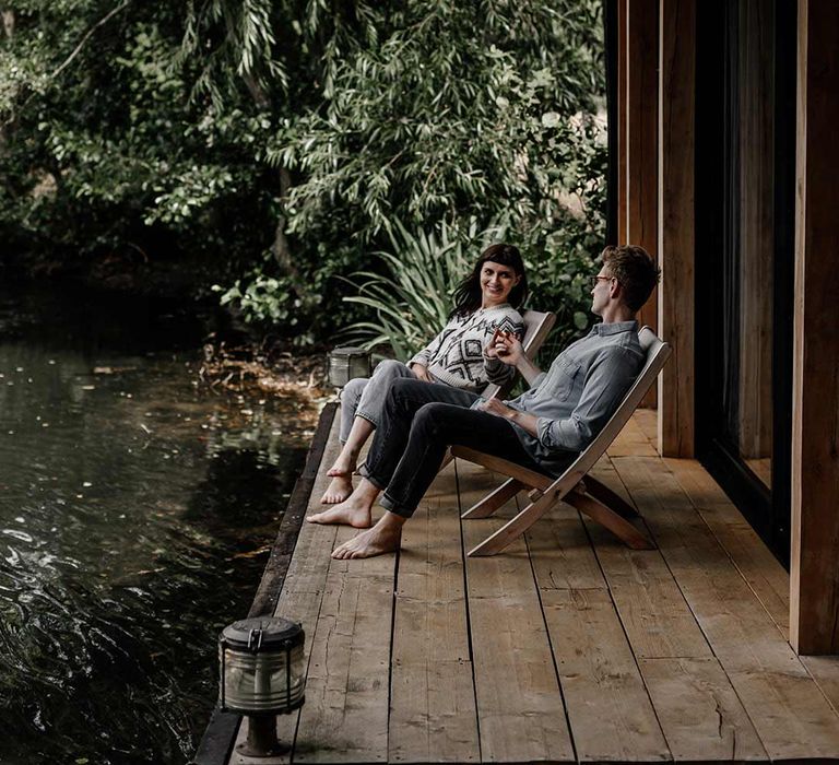 Bride and groom on artistic deck chairs on a pier next to a lake from Prezola wedding gift list 