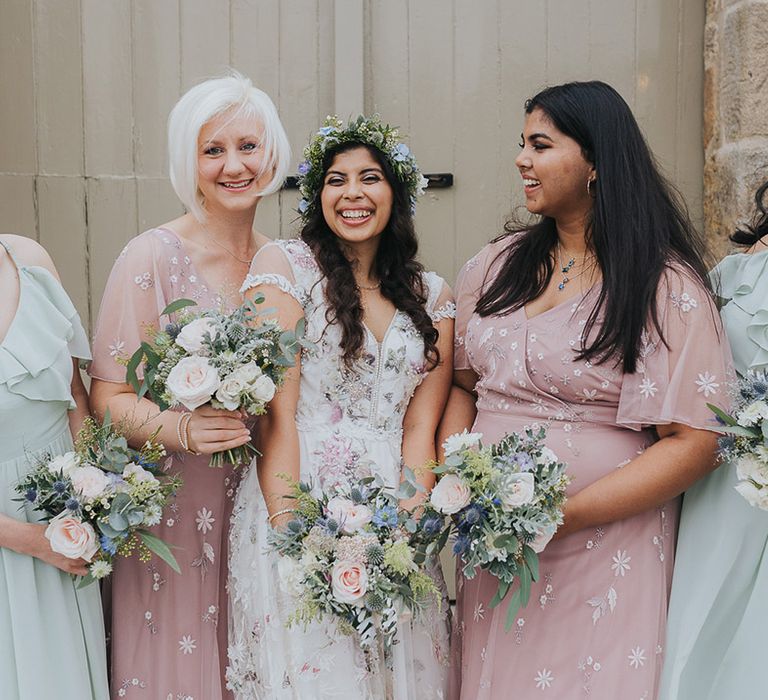 Bridal party in mismatched bridesmaid dresses holding pastel wedding bouquets 