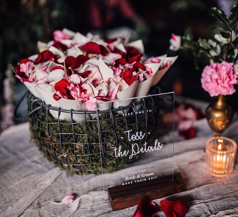 Acrylic wedding sign asking guests to take confetti from the basket full of cones of petal confetti