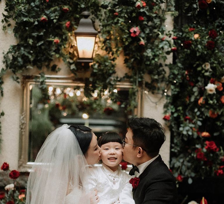 The bride and groom each kiss one of their daughter's cheeks for cute wedding photo