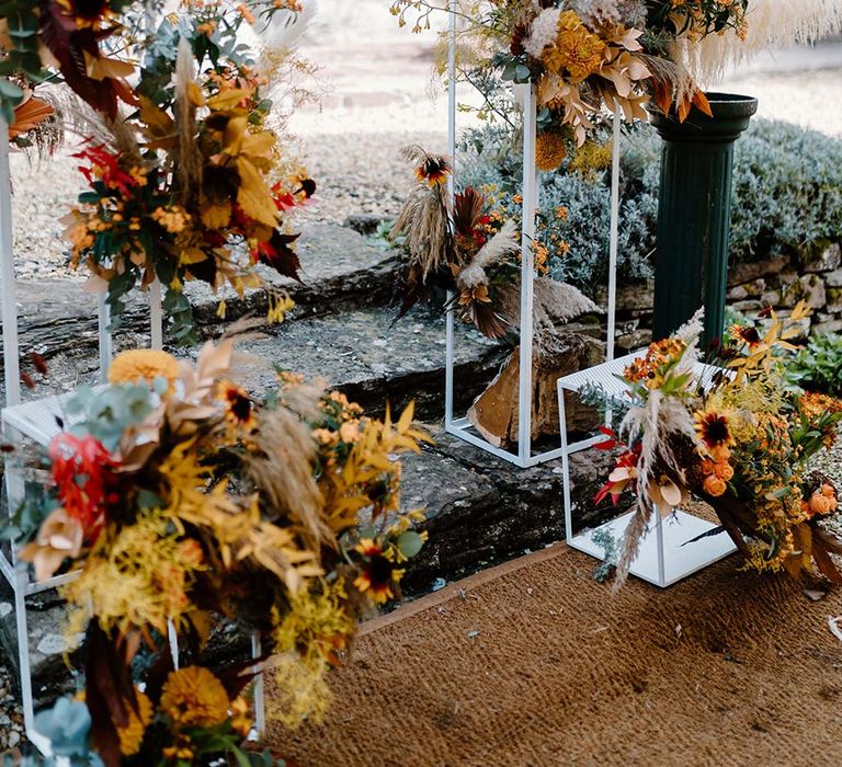 Dried autumnal wedding flower display at the alter of Broadfield Court with sunflowers, garden roses, pampas grass, eucalyptus, yellow tall kangaroo paws, orange osmanthus flowers, foliage and dried flowers 