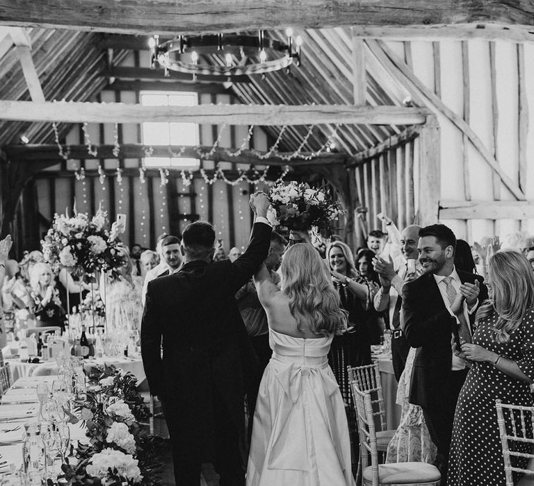 Villiers Barn wedding with the groom walking into the wedding reception with the bride in a bow back design statement wedding dress 