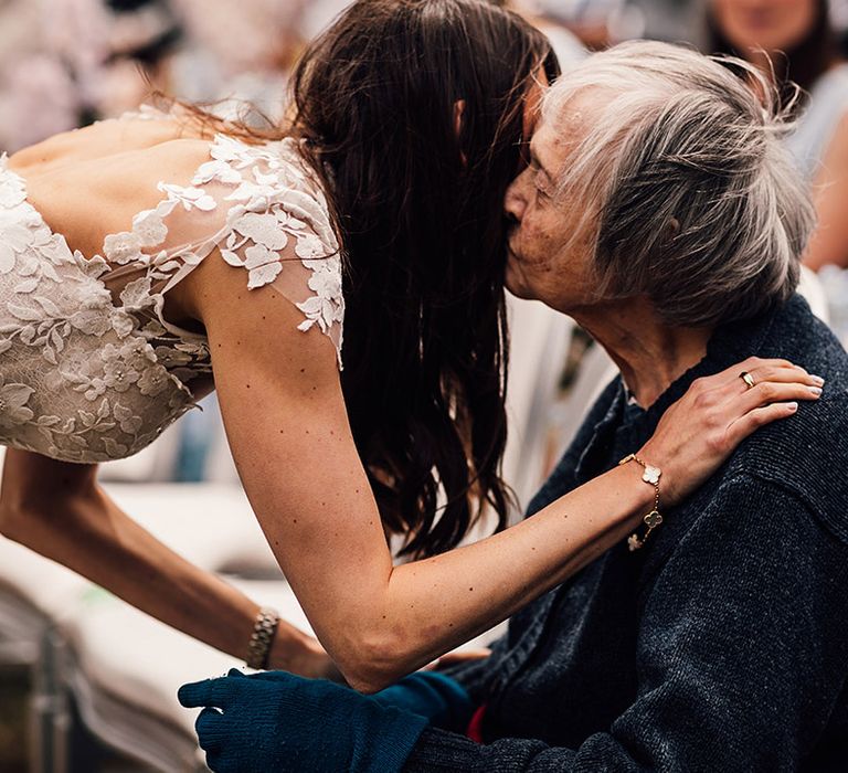 Bride kisses grandparent sitting at the outdoor ceremony at the Four Season Hampshire wedding 