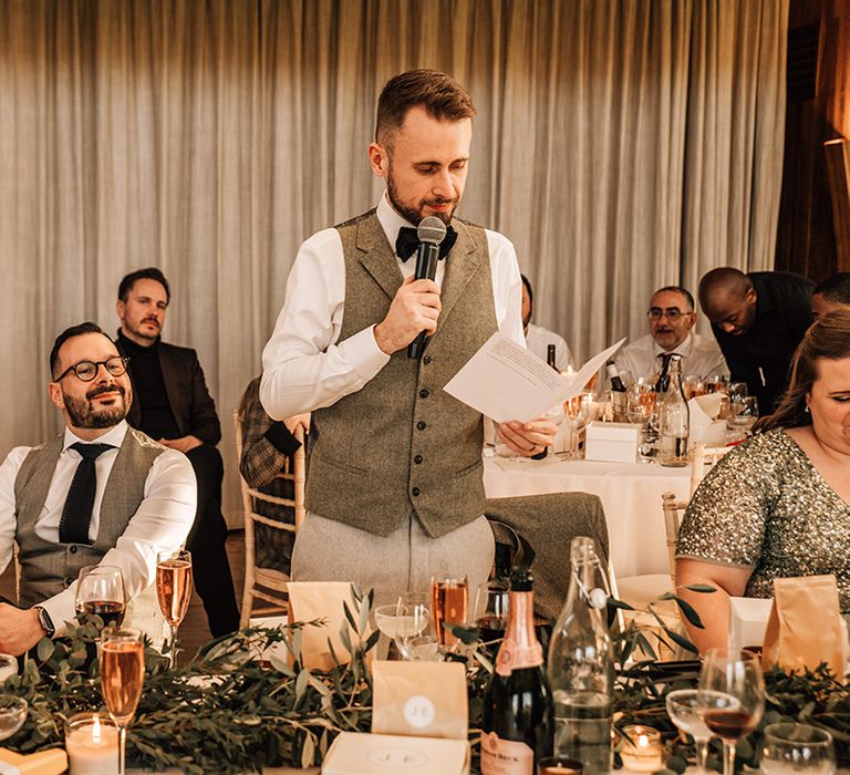 Groom stands with microphone to read out his wedding speech 