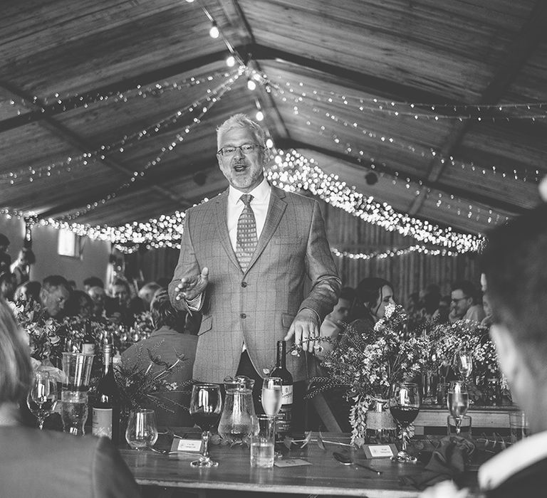 wedding guest in a check suit talking to the wedding party on the top table 