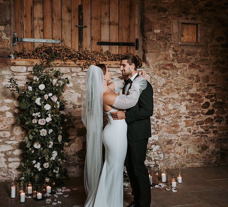 Wedding flower column decorations with the bride wearing a Made With Love wedding dress and groom in traditional black tux 