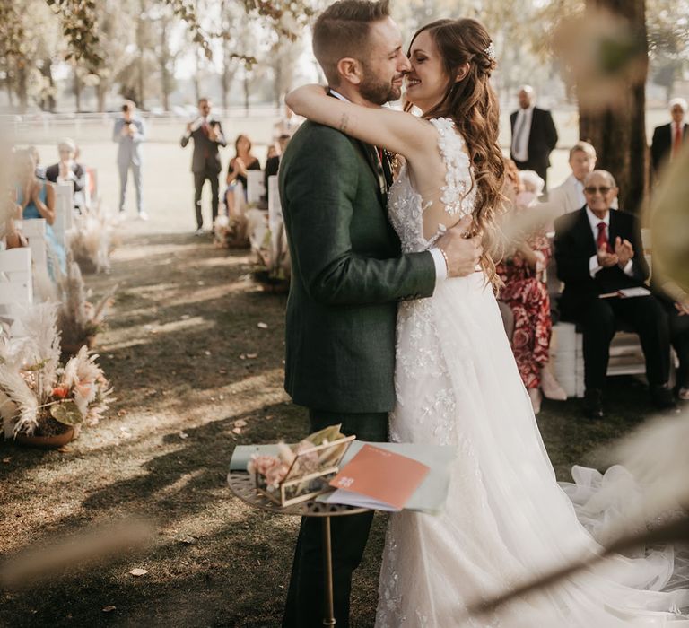 bride in an applique Wedding dress kissing her husband at their outdoor boho wedding ceremony at tenuta il cigno 